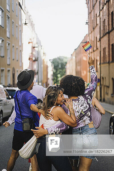 Glückliche junge Freunde gehen auf der Straße während der Gay Pride Parade