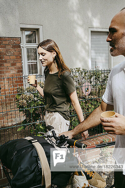 Junge Frau mit männlichem Freund  der mit dem Fahrrad fährt  während er Kaffee trinkt
