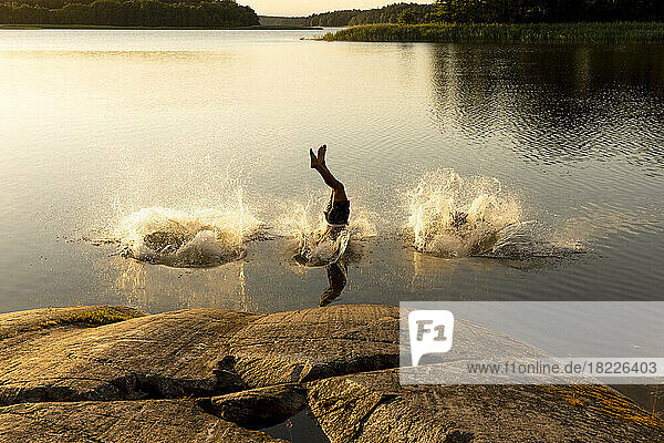 Man diving and splashing water in lake at sunset
