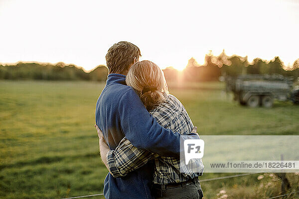 Couple hugging each other on field during sunset