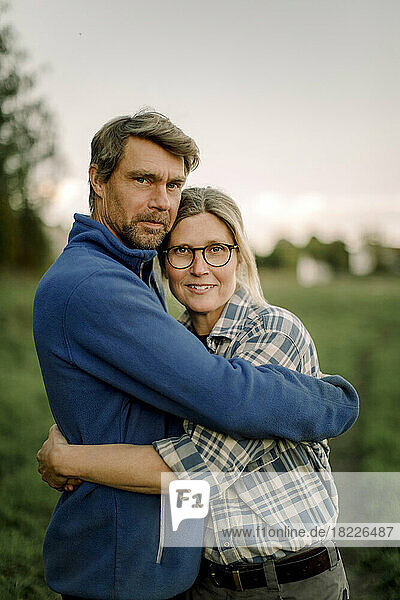 Glückliches Paar  das sich bei Sonnenuntergang auf einem Feld umarmt