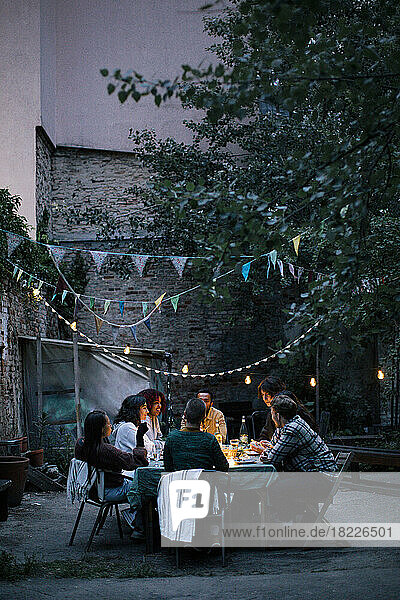 Group of friends enjoying during dinner party in decorated back yard