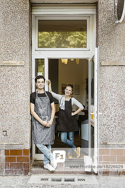 Männliche und weibliche Besitzer stehen zusammen in der Nähe der Tür eines Cafés