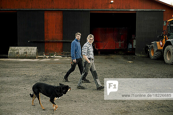 Landwirte mit Hund gehen gemeinsam vor der Fabrik spazieren