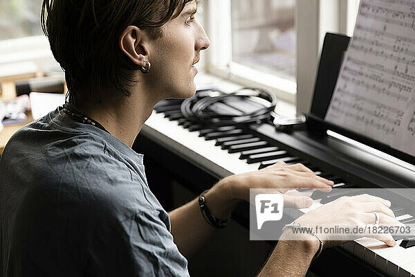 Konzentrierter junger Mann  der zu Hause Klavier übt