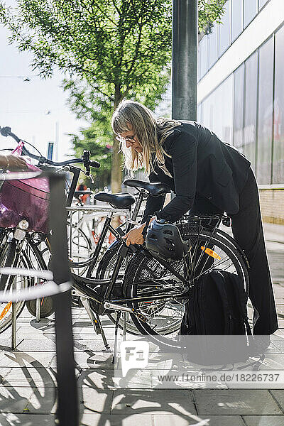 Geschäftsfrau schließt ihr Fahrrad an einer Parkstation ab