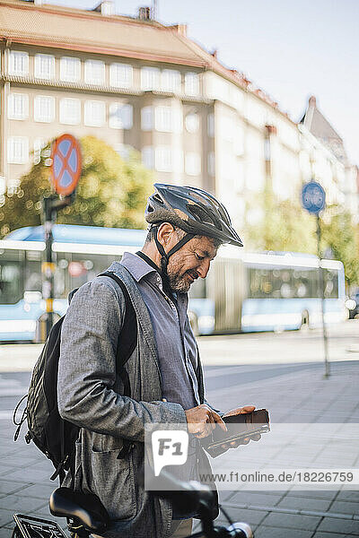 Älterer Geschäftsmann  der ein Smartphone benutzt und auf der Straße steht