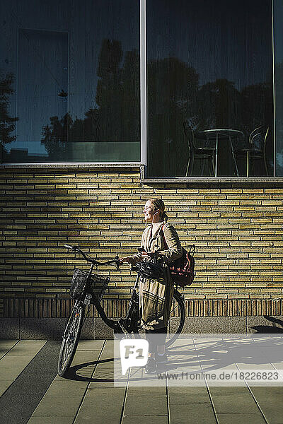 Geschäftsfrau mit Fahrrad vor einer Wand stehend