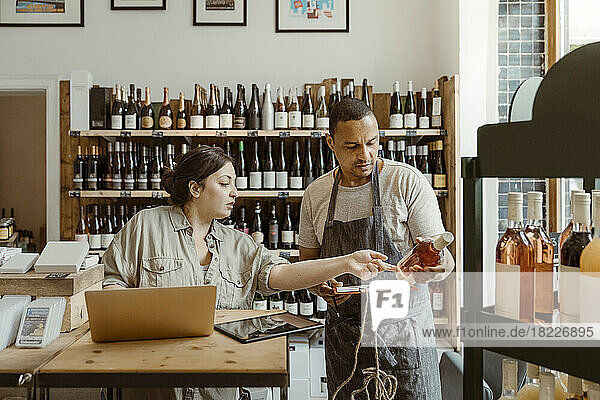 Ein Mann und eine Frau unterhalten sich in einem Geschäft über eine Weinflasche