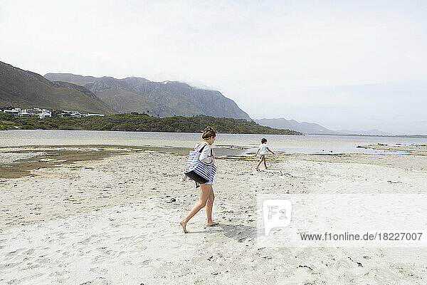 South Africa  Hermanus  Teenage girl (16-17) with brother (8-9) walking on sandy beach