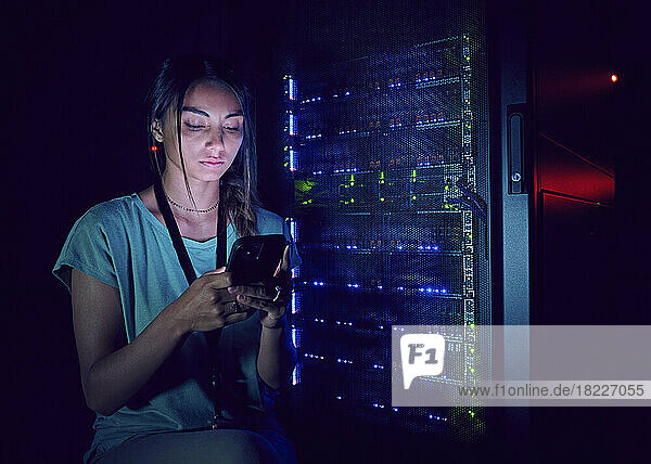 Technician using smart phone in server room