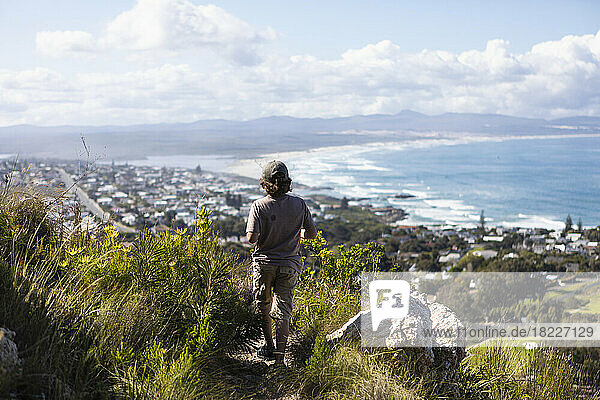 South Africa  Hermanus  Boy (8-9) looking at sea coast from hiking trail in mountains