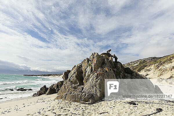 South Africa  Gansbaai  Teenage girl (16-17) with younger brother (8-9) climbing on rock on beach
