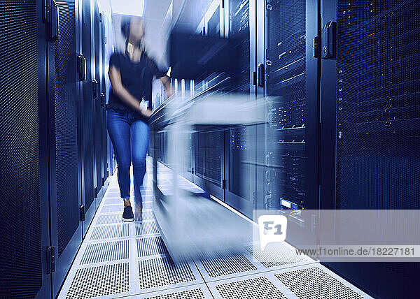 Female technician walking in server room  blurred in motion