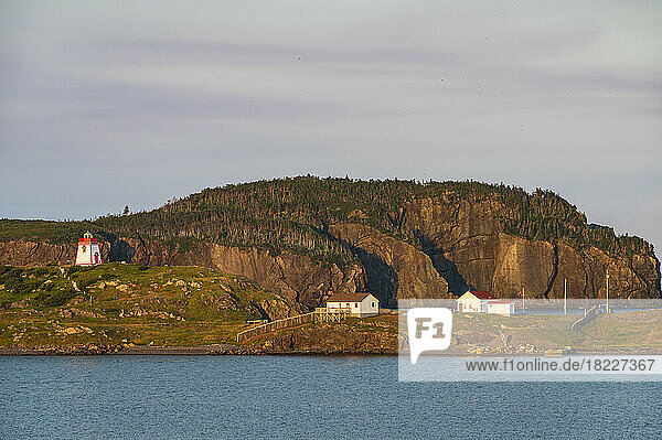 Canada  Labrador  Newfoundland  Trinity  Sea coastline with distant Fort Point Lighthouse at sunset