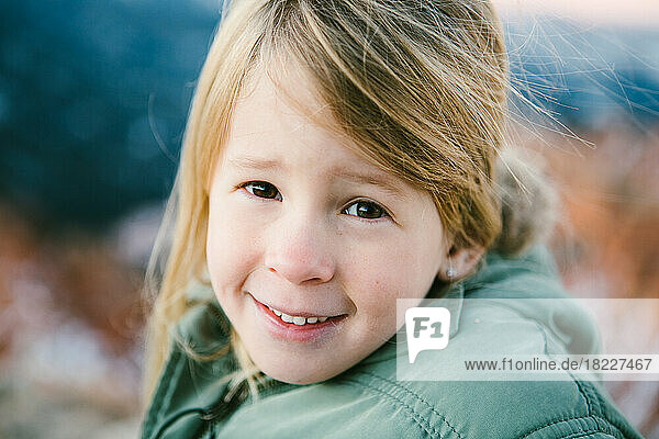 Brown eyed girl smiles over looking red rock canyon with snow