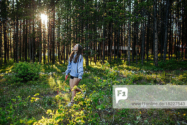 Teen girl in forest holding a racket looking up