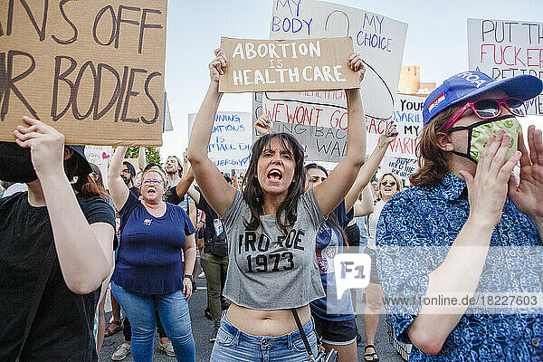 An angry woman stands in crowd holding pro-choice sign at rally