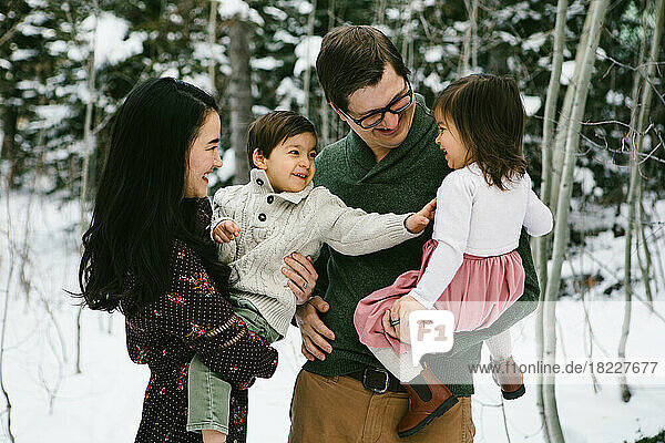 Multi racial family laughs and tickles in snowy local
