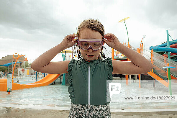 Close up of young girl putting on goggles at a swim park