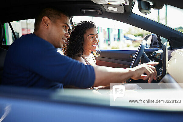 Smiling couple using GPS while sitting in electric car