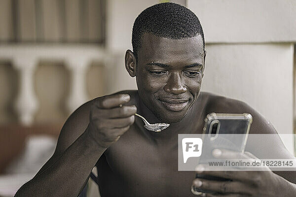 Black man using smartphone during breakfast