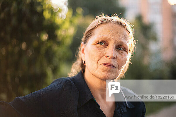 Portrait of thoughtful mature business woman looking away in park