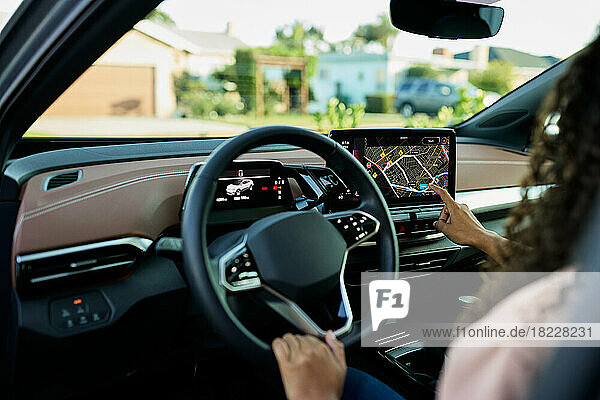 Woman holding steering wheel using GPS system in electric car