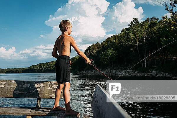Young boy fishing off dock on sunny summer day