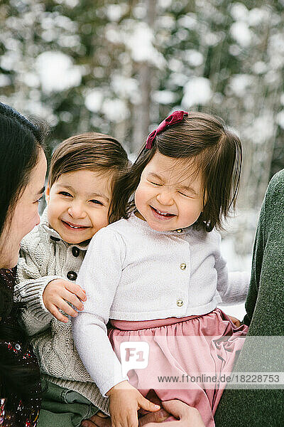 Toddler brother and sister laugh and smile in snow forest