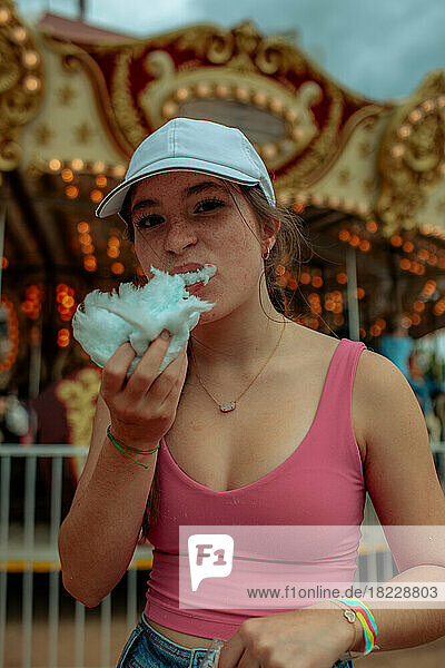 Teen girl eating cotton candy at a carnival