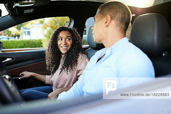 Smiling woman talking with boyfriend sitting in car