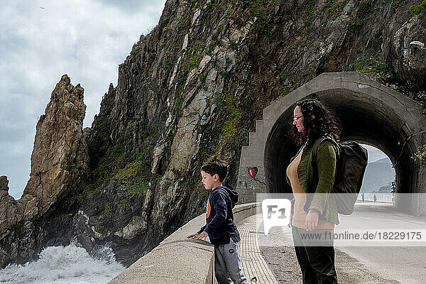 Italy  Sicily  Woman and boy (6-7) standing on roadside looking at?sea waves