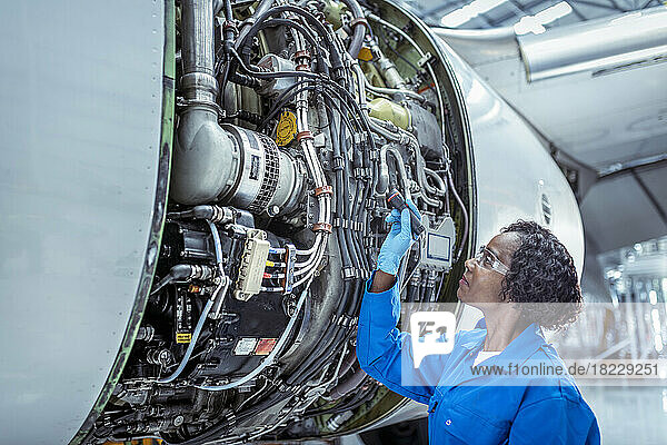 Female aircraft maintenance engineer inspecting jet engine