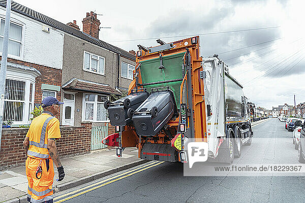 Refuse collector and refuse truck in street