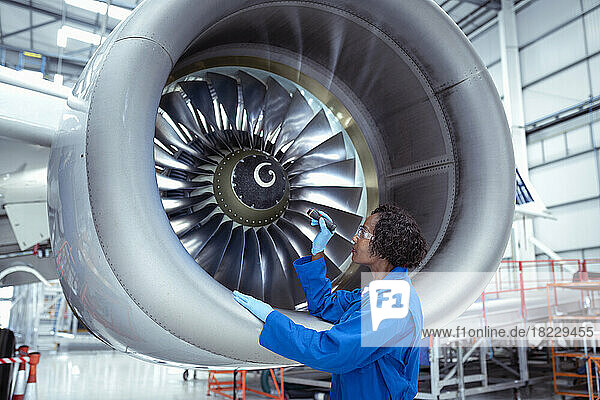 Female aircraft maintenance engineer inspecting large jet engine