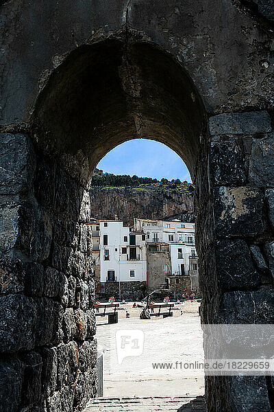 Old town square seen through stone arch  Sicily  Italy