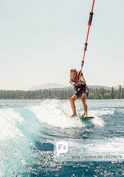 Boy (8-9) wakeboarding at lake