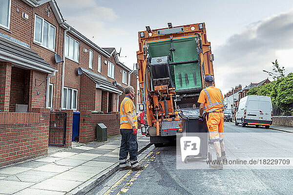 Refuse collectors and refuse truck in street