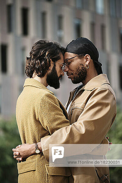 Schwules Paar mit geschlossenen Augen umarmt sich vor dem Gebäude