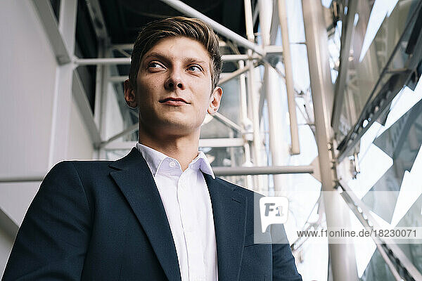 Thoughtful young businessman standing in front of scaffolding