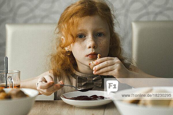 Redhead girl having breakfast at home