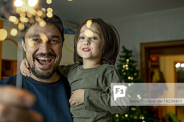 Happy father with son holding sparkler at home