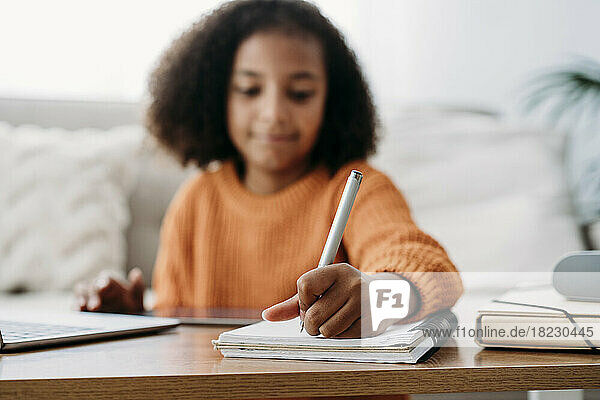 Girl with pen and notepad doing homework at home