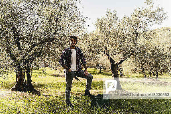 Happy man with hand in pocket at olive orchard