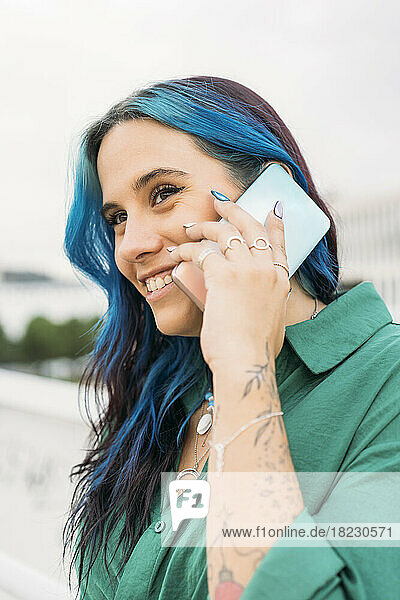 Woman with blue highlighted hair talking on smart phone