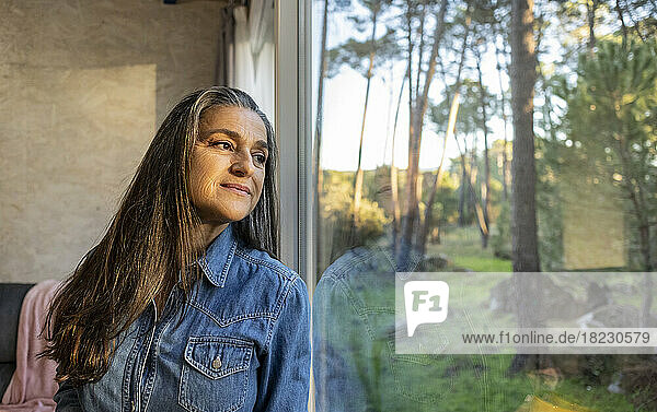 Mature woman at home looking out of window
