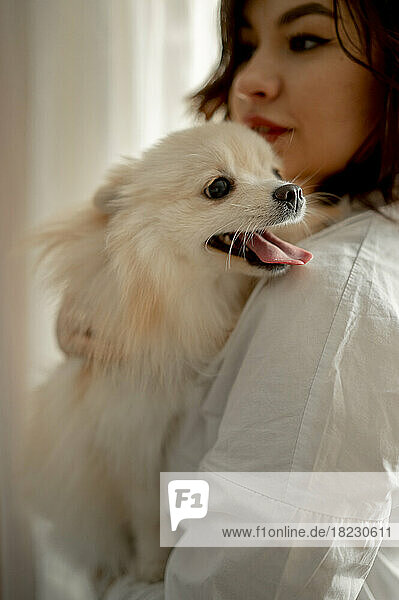 Beautiful young woman with Pomeranian dog at home