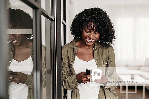 Smiling woman using smart phone at home