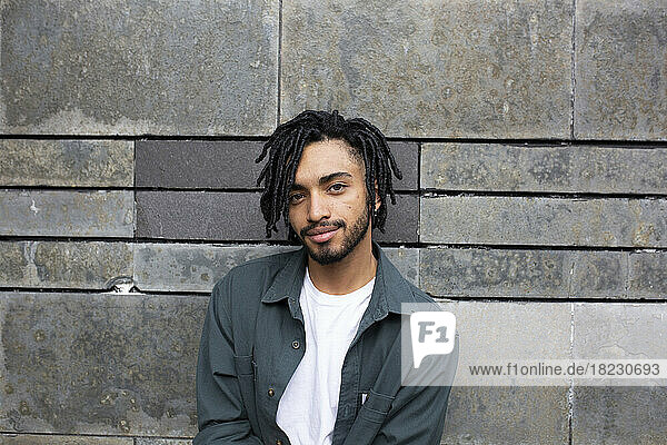 Young man with dreads in front of wall